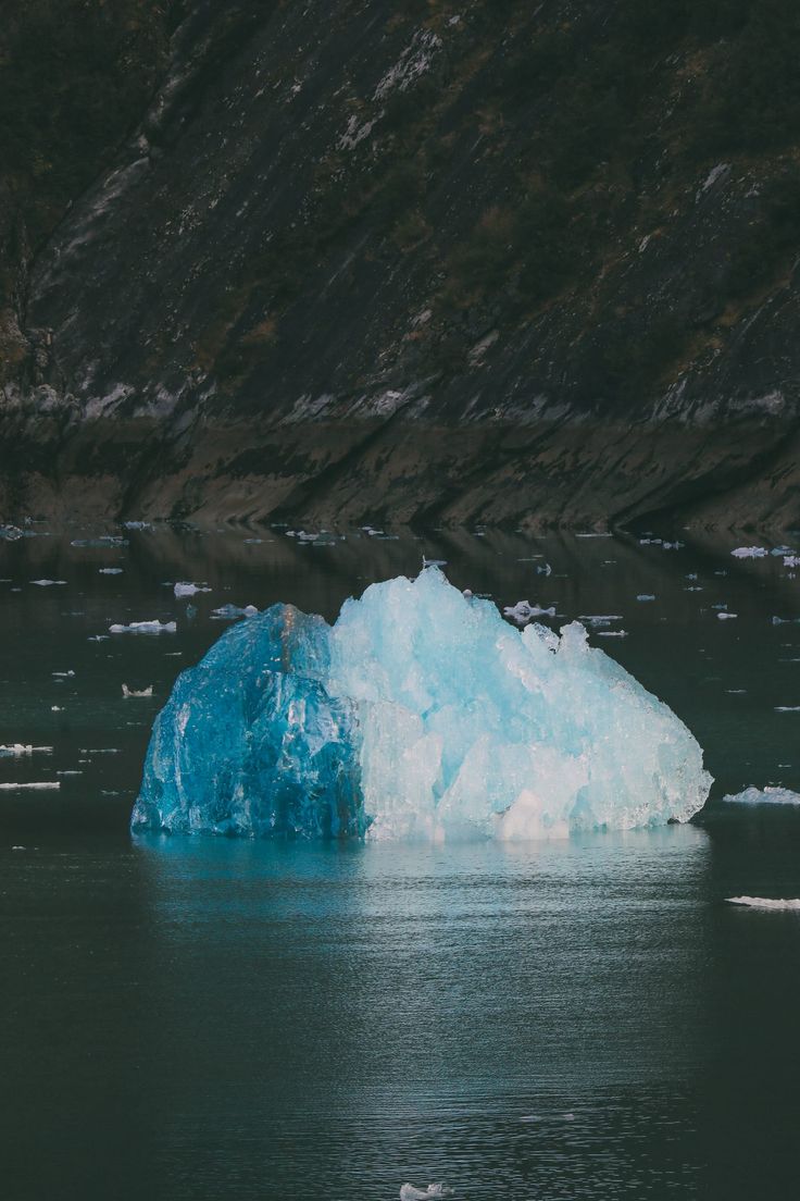 an iceberg floating in the water near some mountains