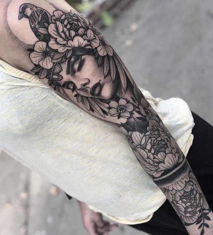 a woman's arm with flowers on it and a bird in the middle of her arm