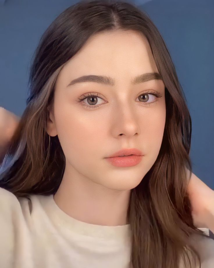 a woman with long brown hair wearing a white shirt and holding her