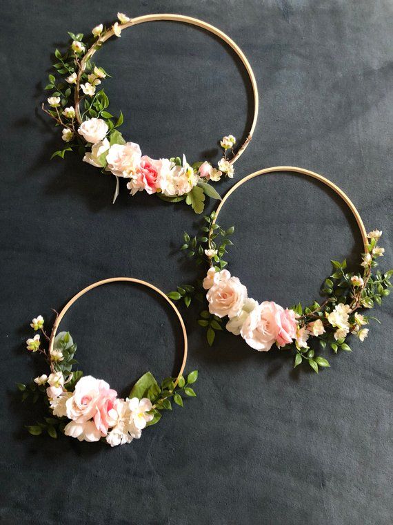 two gold hoop wreaths with pink and white flowers on black fabric, ready to be used as decoration