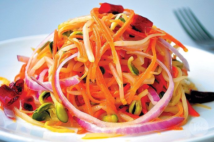 a white plate topped with carrots, onions and sprouts next to a fork