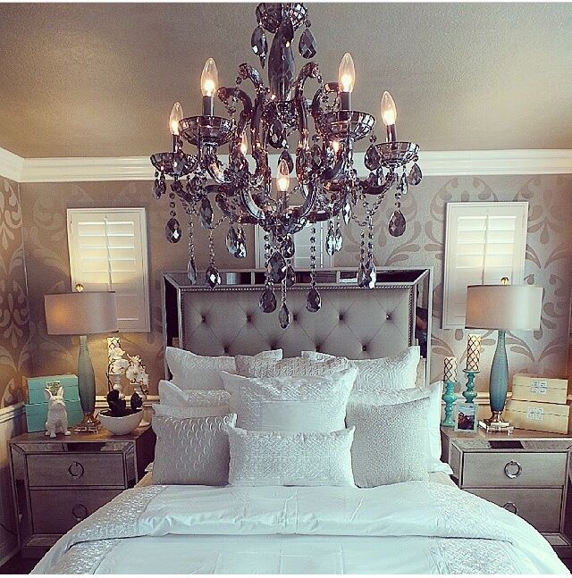 a bedroom with a chandelier hanging over the bed and pillows on the floor