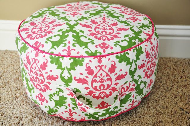 a large colorful ottoman sitting on top of a carpeted floor next to a wall