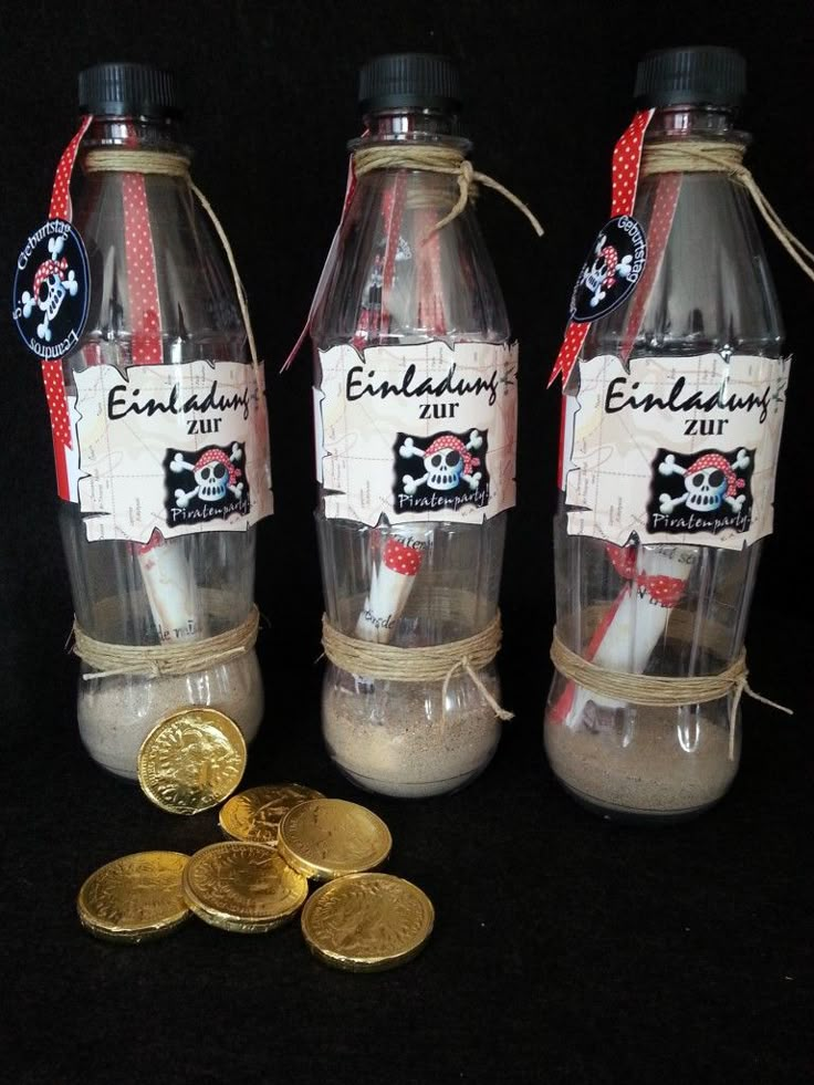 two clear bottles filled with sand next to some gold coins