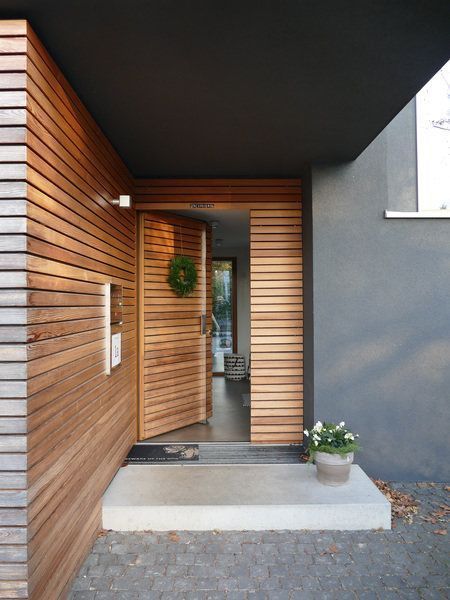 an entrance to a modern home with wood slats on the wall and door frame