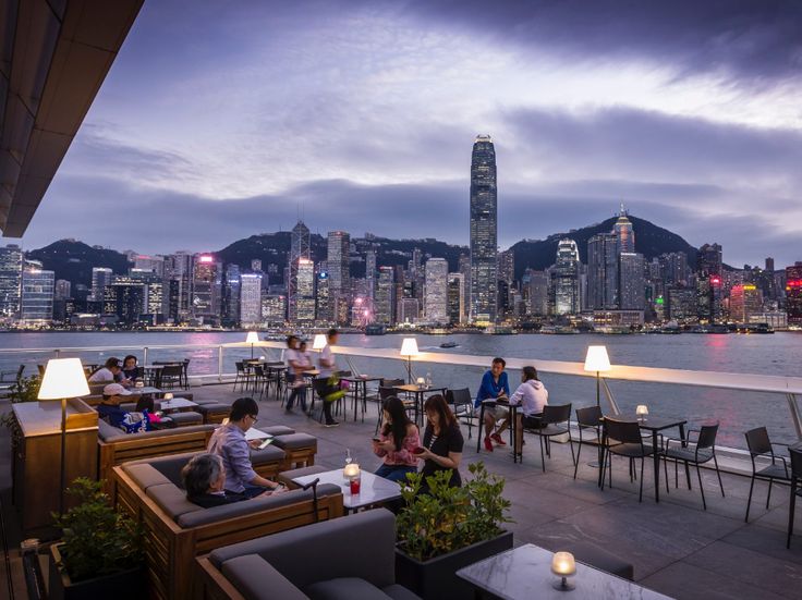 People Are Sitting At Tables Overlooking The Water In Front Of A People Are Sitting At Tables Overlooking The Water In Front Of A