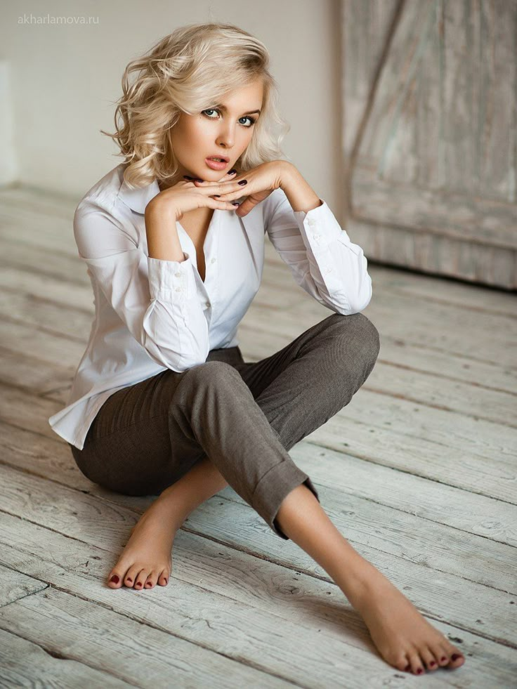 a woman sitting on the floor with her legs crossed and looking off to the side