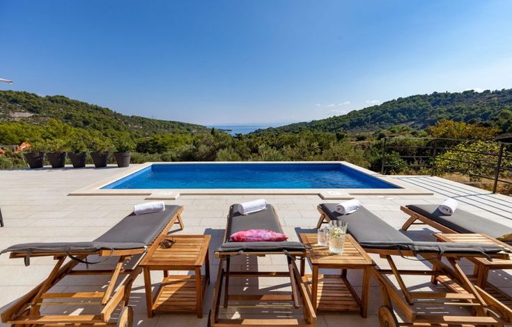 an outdoor table and chairs near a swimming pool