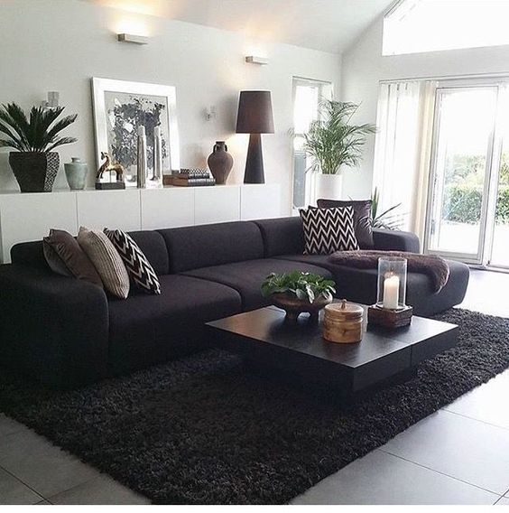 a living room filled with black furniture and lots of pillows on top of a rug