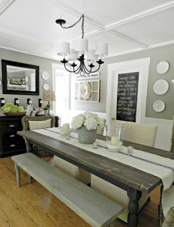 the dining room table is set with white flowers in vases and plates on the wall