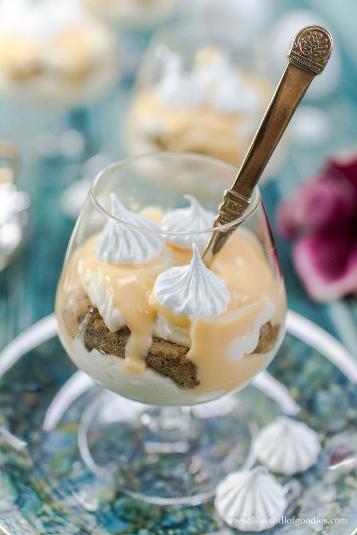 a dessert in a small glass dish on a blue tablecloth with shells and flowers