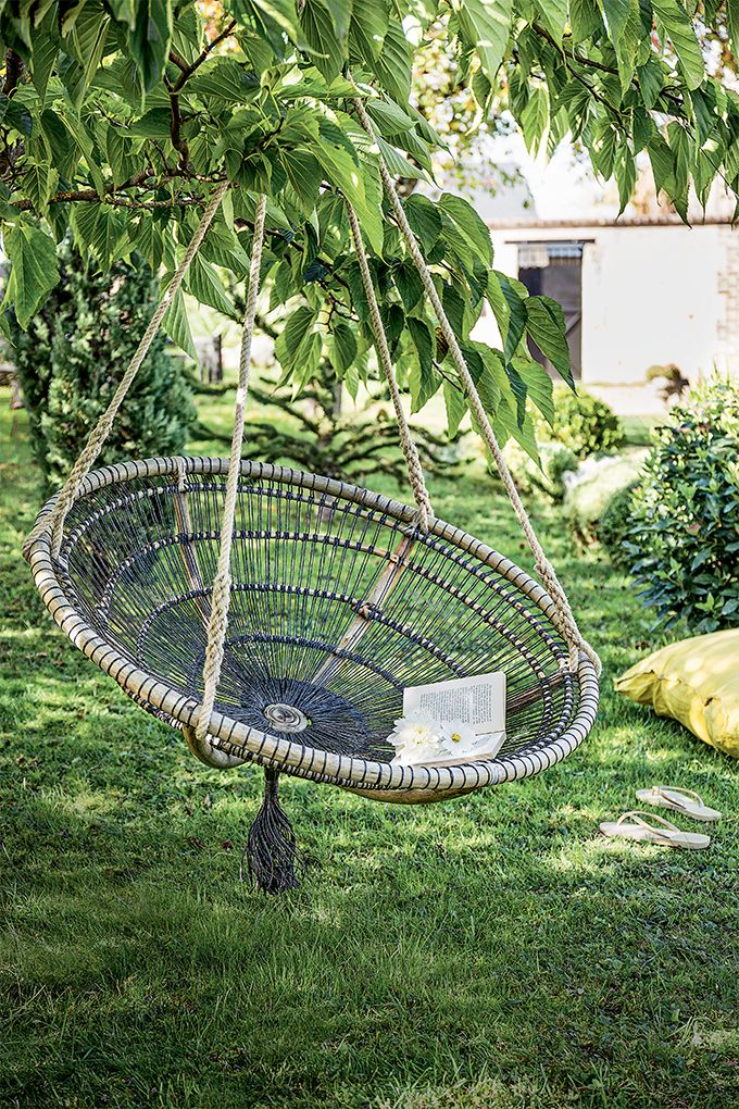 a hammock hanging from a tree branch in the grass with a book on it