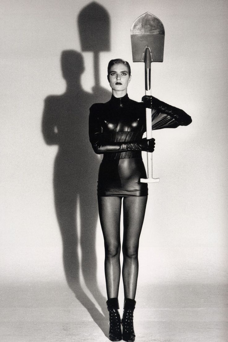 a black and white photo of a woman in tights with a mop on her shoulder