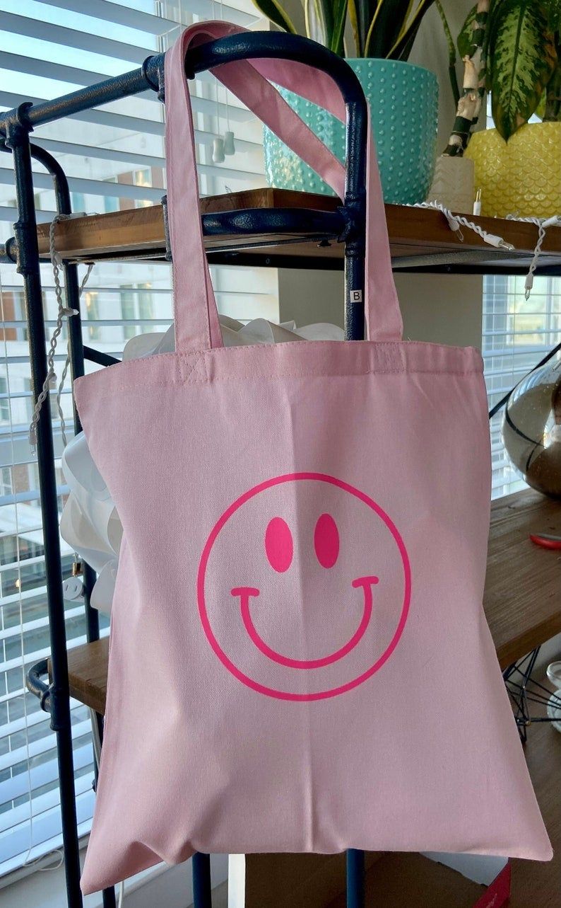 Large Pink Smiley | 100% Cotton Canvas Tote | Screen PrintThe Details:Large size tote: 15x16100% CottonPink Smiley Screen Print TransferCanvas Tote BagDesigned & made in the USA! Summer Tote Bags, Trendy Tote Bags, Cute Tote Bags, Pink Tote Bags, Printed Tote Bags, Cotton Tote Bags, Reusable Tote Bags, Tote Bad, Handpainted Tote Bags