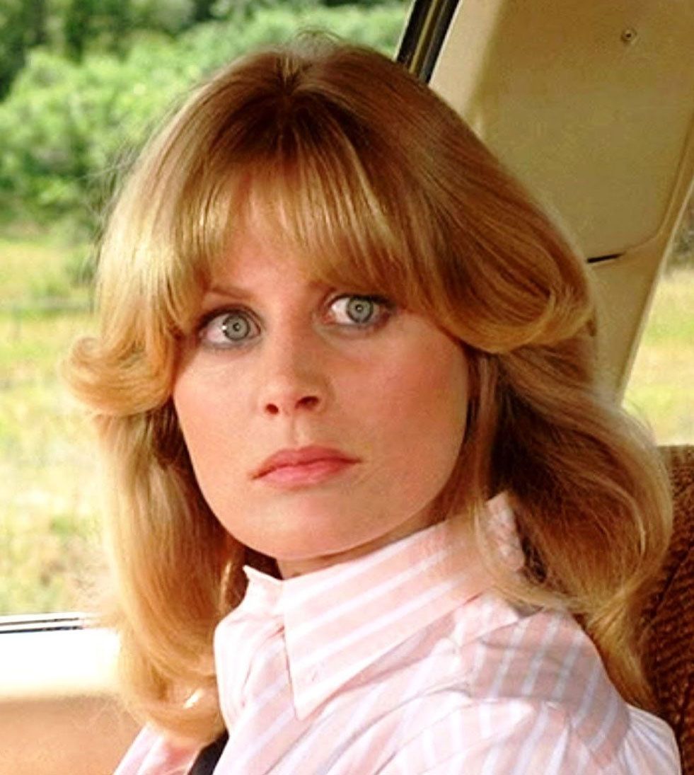 a woman with blonde hair sitting in the back seat of a car looking off