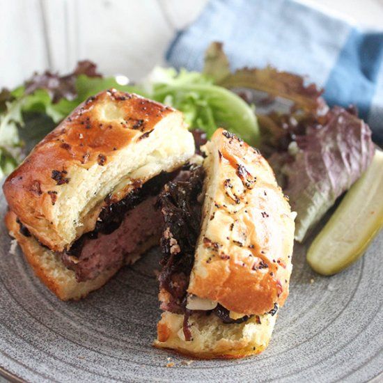 A lean and juicy burger is topped with caramelized onions
