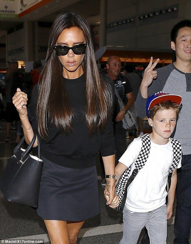David Beckham cradles a sleepy Harper as he and Victoria fly out of LA