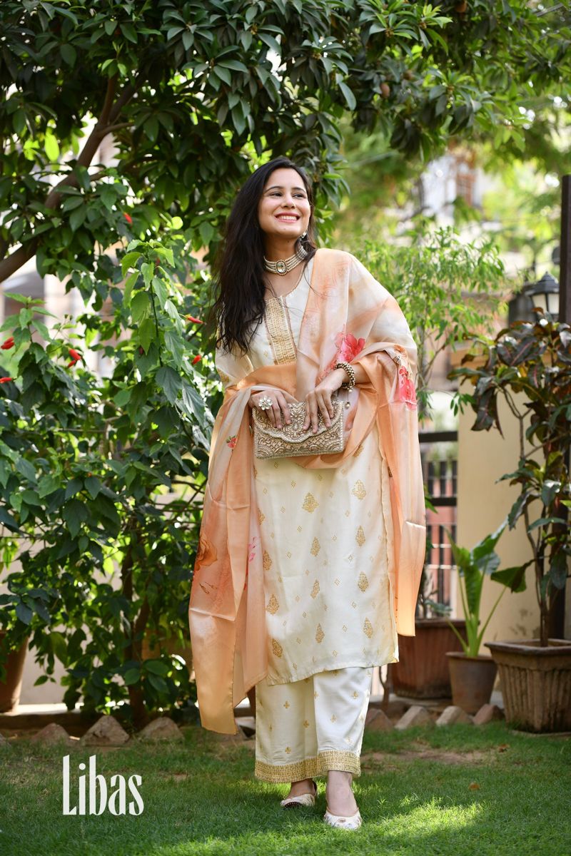 Our 3-piece cream tone floral print silk blend suit set features a straight-fit kurta with a notched neckline, three-quarter sleeves and handcrafted dori-details on the sides, flared palazzo pants with a partially elasticated waistband and roomy pockets, and a complementing multicolour satin dupatta. Adorned with Gota Patti and fabric-trim accents, this elegant style is ideal for casual outings. #LibasWomen #LibasIndia #IndianWear #SilkSuit #EthnicWear #FestiveWear #EmbroideredSuit Flare Palazzo Pants, Flared Palazzo, Cream Tones, Silk Suit, Metal Lace, Fabric Trim, Festival Wear, Different Fabrics, Indian Wear