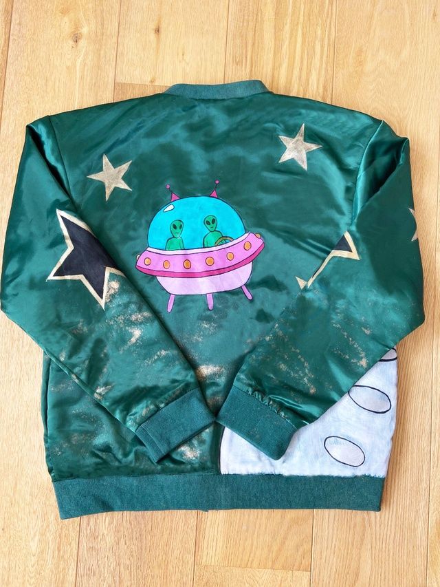 Green luxe premium satin bomber jacket with a bespoke in house design retro leopard print formed of a sequence of leopards, chains and jewels. We have up cycled our green satin bomber jacket by hand painting gold stars, all over the jacket, black stars at the elbow and at the back aliens in a space ship trying to land on the moon. A cool and One Off jacket which is bound to get heads turning as its so unique. Matching mask in boutique. Moon Landing, Satin Bomber Jacket, Rolla, Leopards, Green Satin, Black Star, Gold Stars, Aesthetic Clothes, Leopard Print