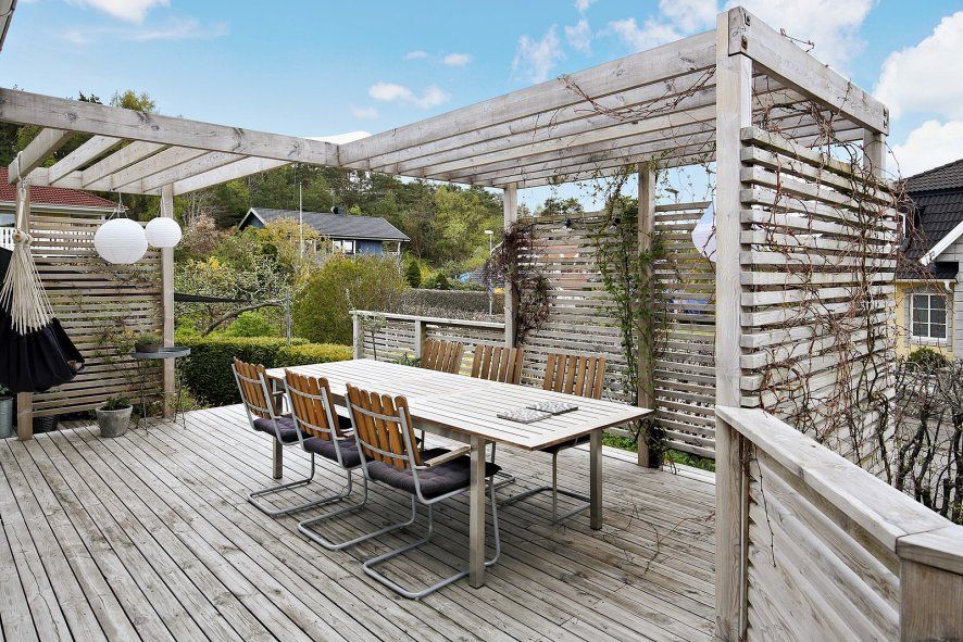 Vacker och insynsskyddad uteplats utanför köket med pergola ...