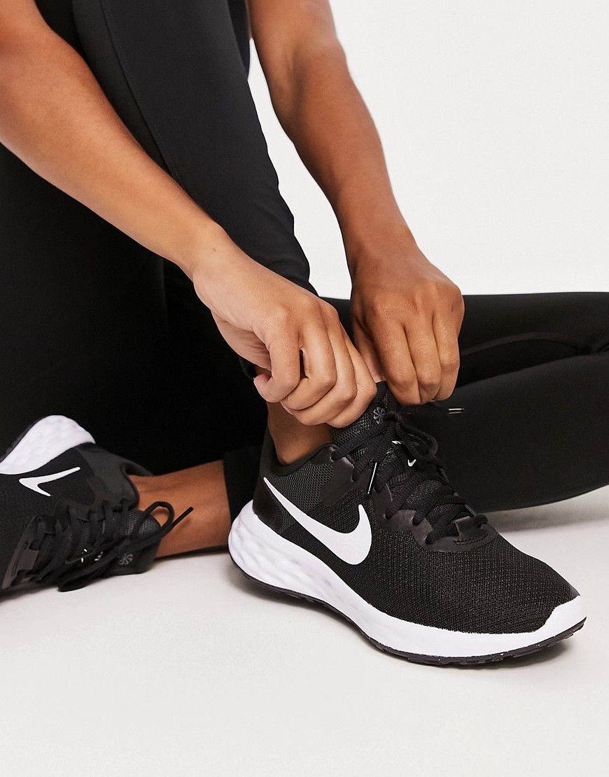 A Woman Tying Her Shoe Laces On Her Black Nike Running Shoes While A Woman Tying Her Shoe Laces On Her Black Nike Running Shoes While