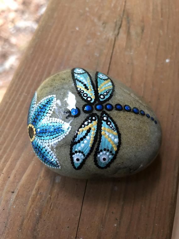 Blue dragonfly and flower dot painted on rock Blue dragonfly and flower dot painted on rock