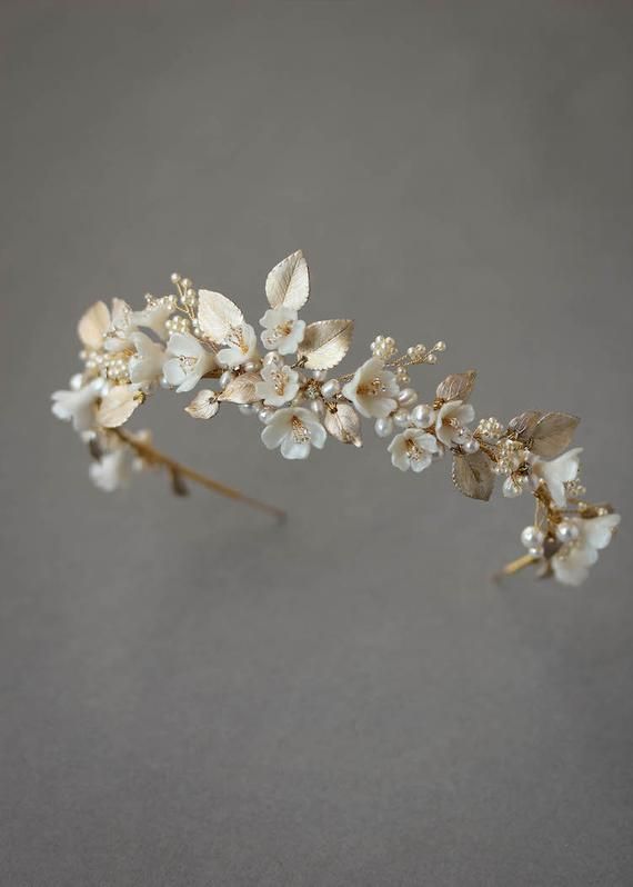 LIMITED QUANTITIES: Due to the popularity of the Flores crown, we have limited materials available to create this design. If you love this headpiece, we recommend you secure it before we are no longer able to recreate it.Flores is a floral wedding crown constructed from a dreamy palette of soft ivory and pale golden tones. Inspired by the softness of light upon delicate blossoms, this floral display is bursting with overgrown details and intricate embellishments. Feminine, fresh and utterly rom Gold Wedding Crowns, Wedding Tiaras, Crystal Bridal Tiaras, Wedding Veils, Wedding Halo, Wedding Crown Tiara, Bride Crown, Bride Tiara, Wedding Garters