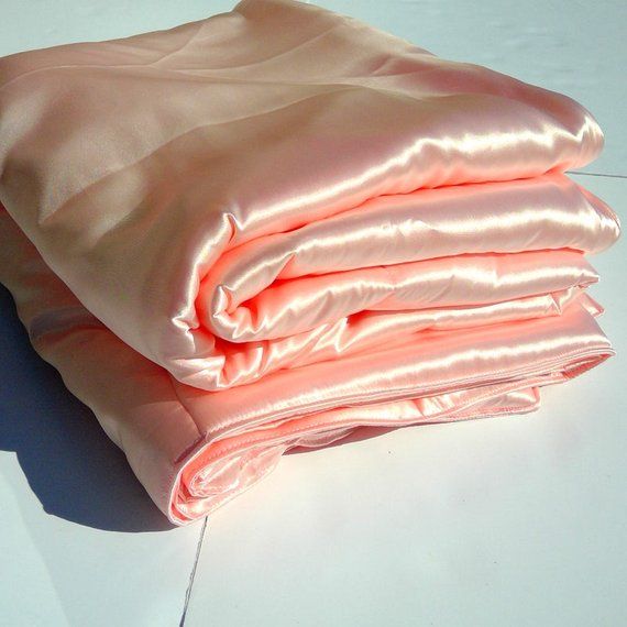 three folded pink sheets sitting on top of a white table next to an ...