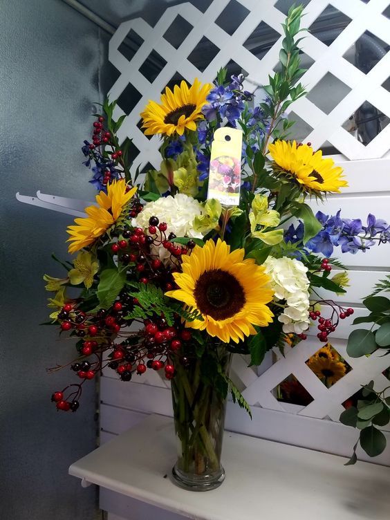 A vase with sunflowers, white hydrangea, green alstromaria ...