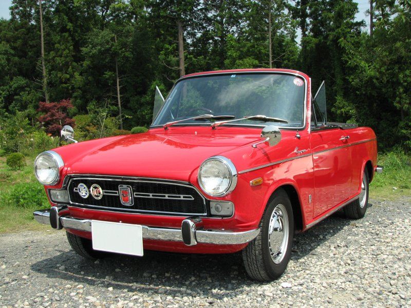 an old red car is parked on the gravel