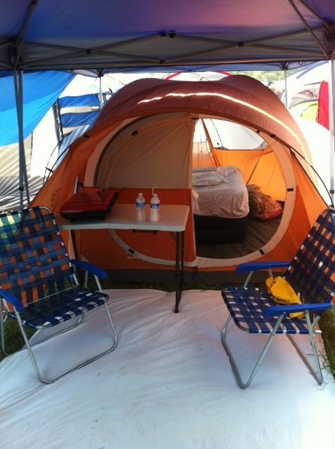 lawn chairs outside tent in corner with blankets on floor festival camping tält