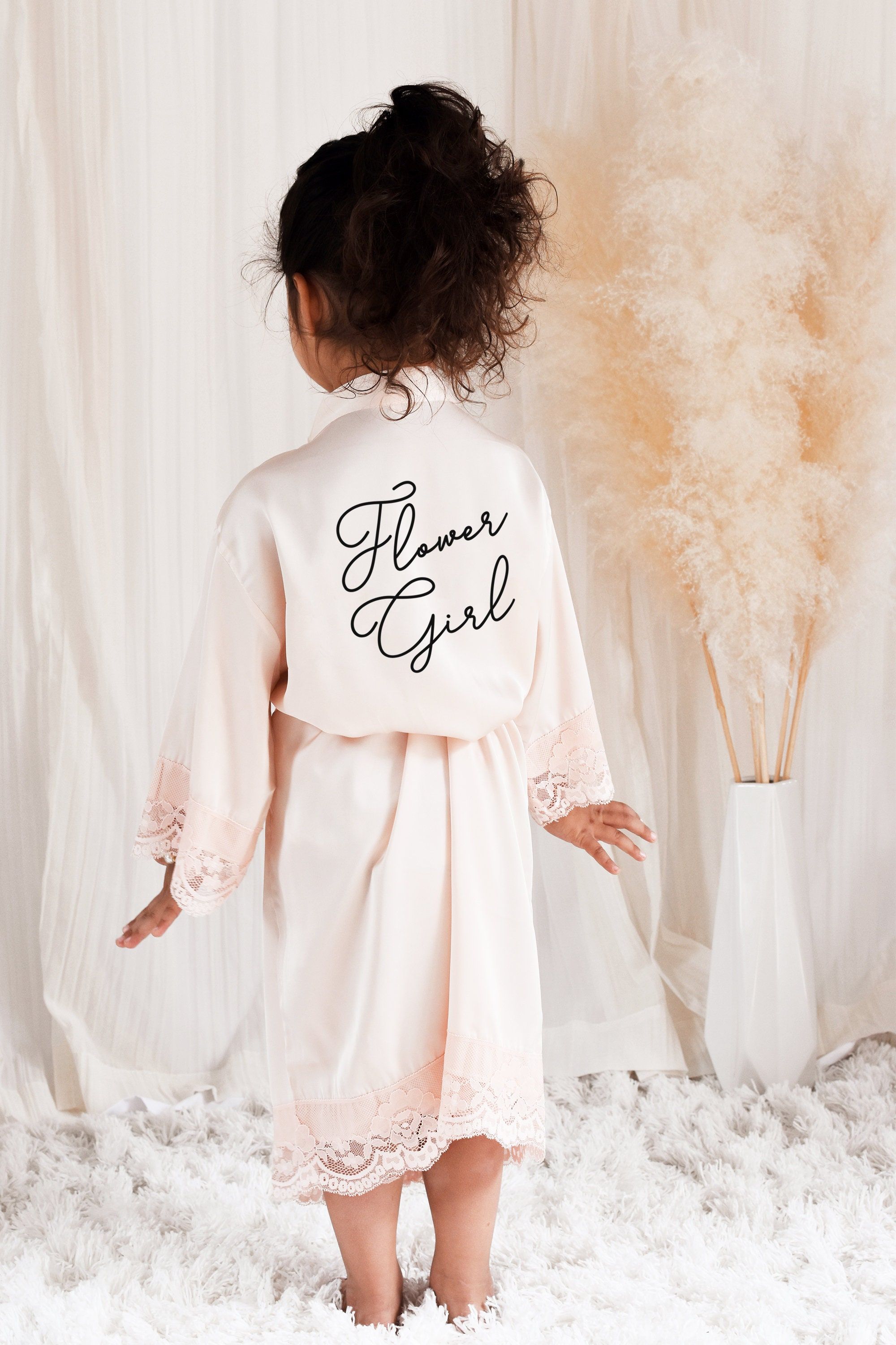 "Flower girls will be \"pretty in pink\" dressed in our delicate satin lace robes. Child size robes come in a delicate blush peach color and are made of soft polyester satin with a lace trim. Robes are printed with \"flower girl\" on the backside in your choice of one of our metallic foil colors or black text. Each robe comes with a matching belt for the outside. Details Listing is for 1 Flower Girl Lace Trimmed Robe in blush peach. ROBE only - other items not included but available in our shop. Flower Girl Hanger, Flower Girl Robes, Lace Flower Girls, Flower Girl Gifts, Baby Flower Girl, Wedding Flower Girl Dresses, Flower Girl Beach Wedding, Asking Flower Girl, Peach Flower Girl Dress