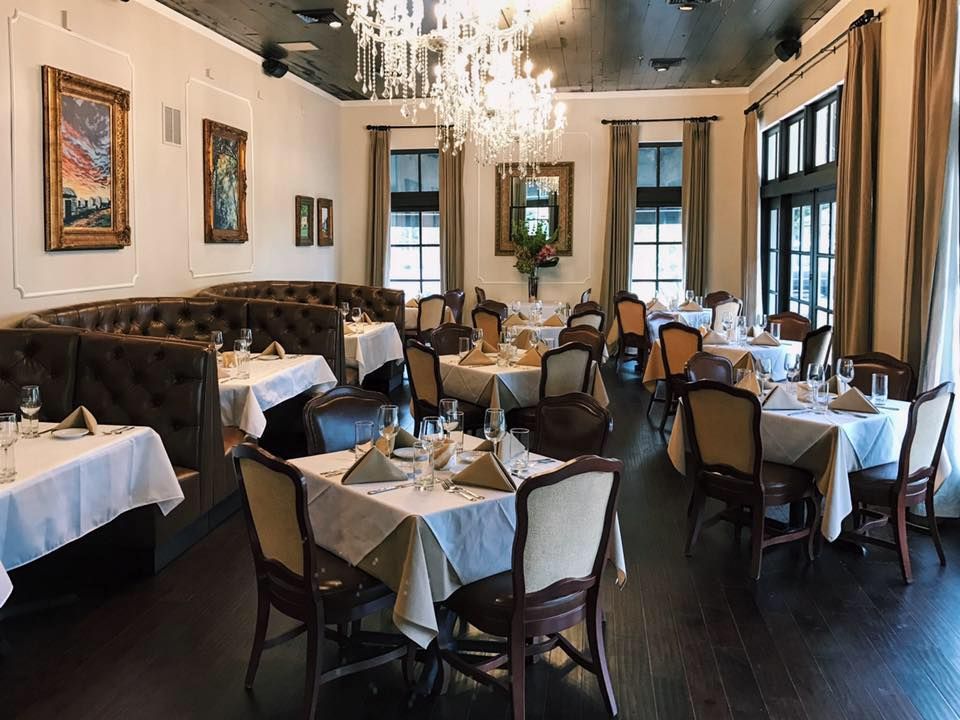 A Dining Room With Tables And Chairs Covered In White Tablecloths a-dining-room-with-tables-and-chairs-covered-in-white-tablecloths