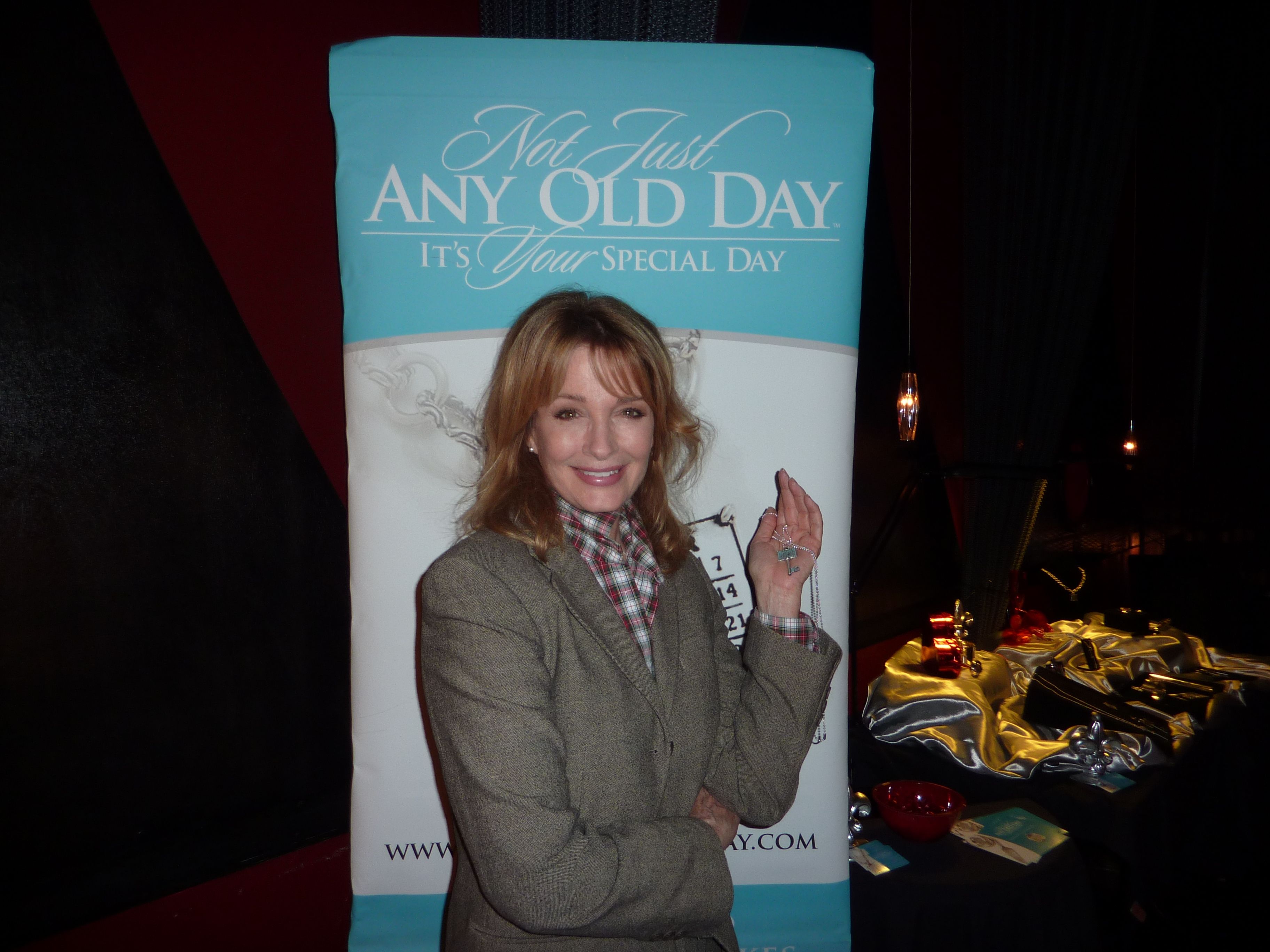 a woman standing in front of a sign with her hand up to the camera and