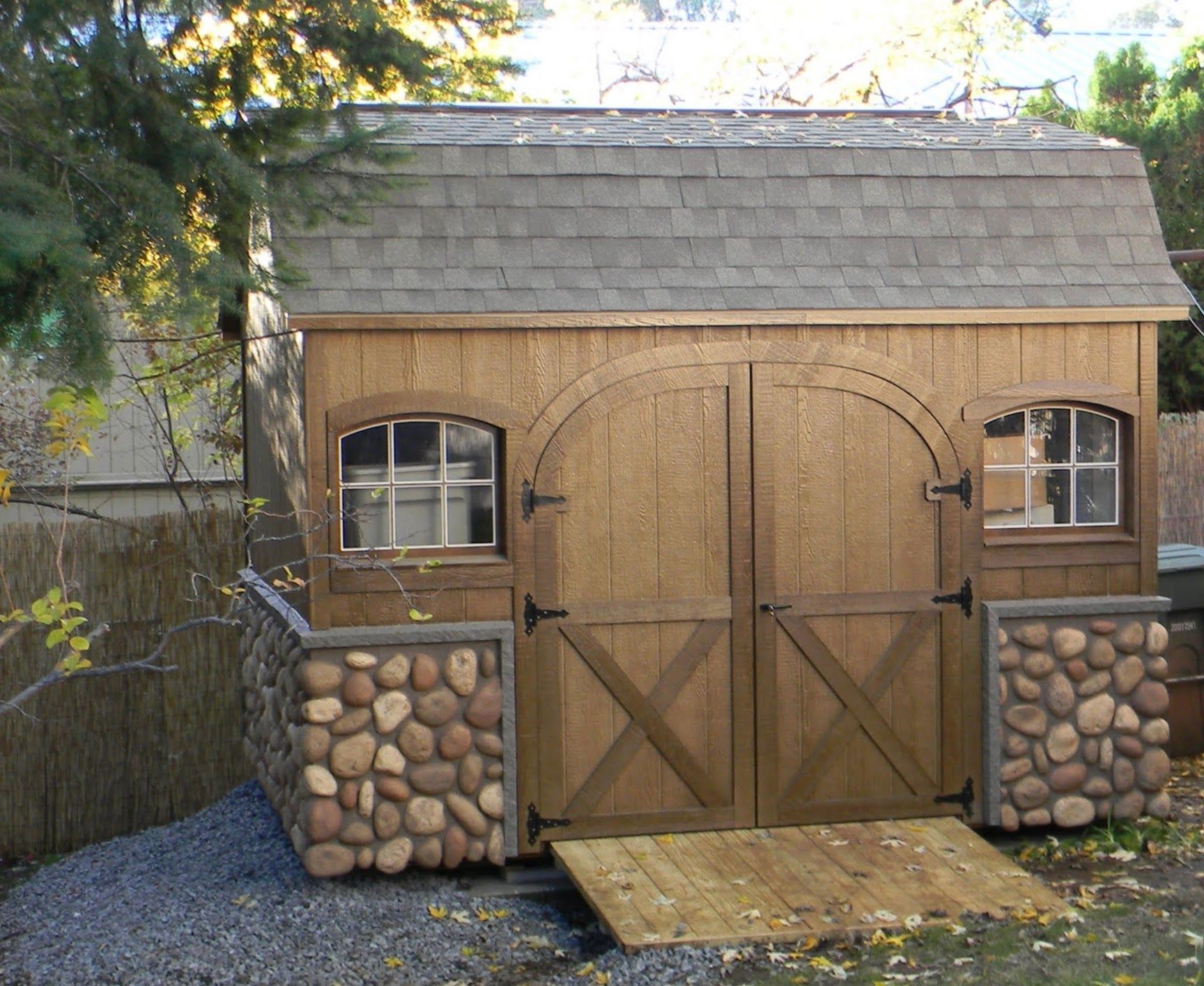 Dutch Colonial Storage Shed with Stone Veneer and Rounded Door