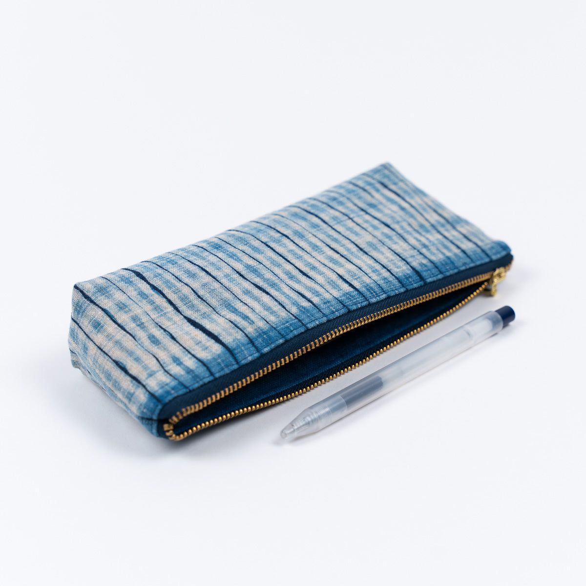 A compact pouch for your stationeries and makeup essentials crafted from our indigo dyed shibori fabric. • Outer material: indigo-dyed linen• Inner lining: indigo-dyed cotton canvas• YKK brass zipper Dimensions: • 9", 3.5", 1.5" (approximately 21x9x4cm) • Please note that due to the handcrafted nature of our works each one is unique and the color/pattern may vary slightly from the images. Shibori Fabric, Stationeries, Dyed Linen, Makeup Essentials, Indigo Dye, Pleats, Color Patterns, Cotton Canvas, Compact