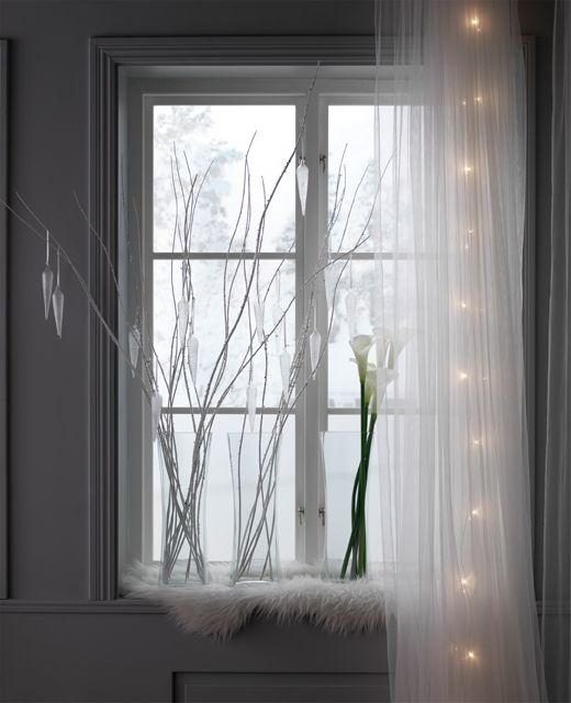 A window with a snowy view is decorate with glass vases, twigs and ...