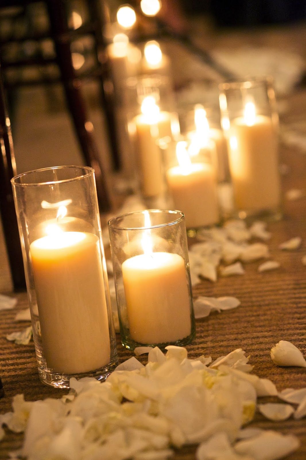 Trio of hurricane candles at every other row of seats (white pillars