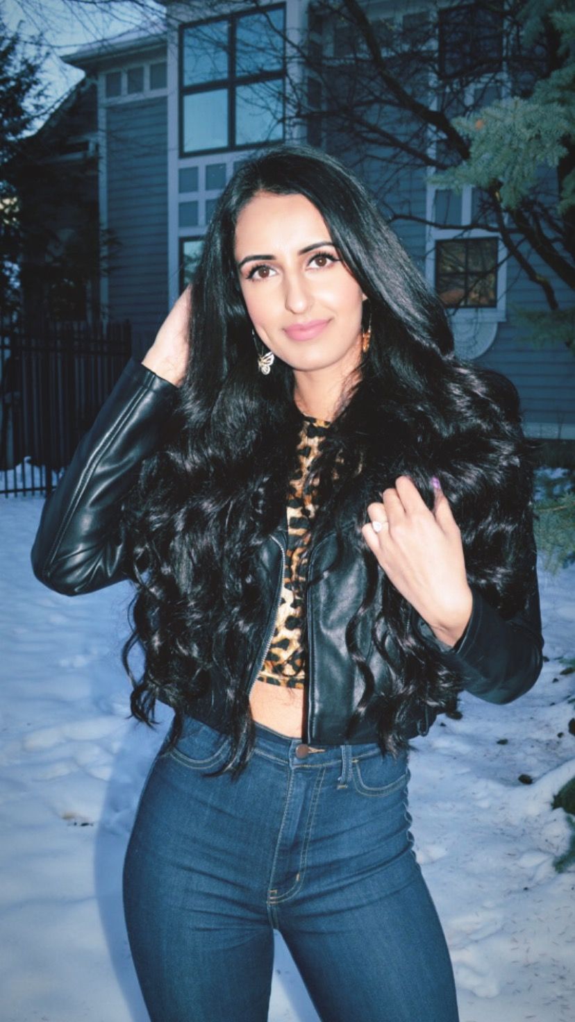 Women’s winter fashion black leather jacket and cheetah crop top with blue skinny jeans