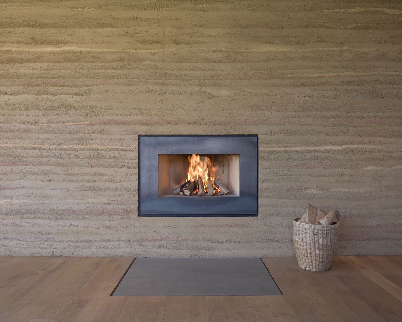 Der Offene Kamin Mit Einem Cor Ten Stahlrahmen Ist In Einer Der Offene Kamin Mit Einem Cor Ten Stahlrahmen Ist In Einer Lehmstampfwand Eingelassen Durch Ein Kleines Fenster Das Feuer Auch Von Anderen Seite