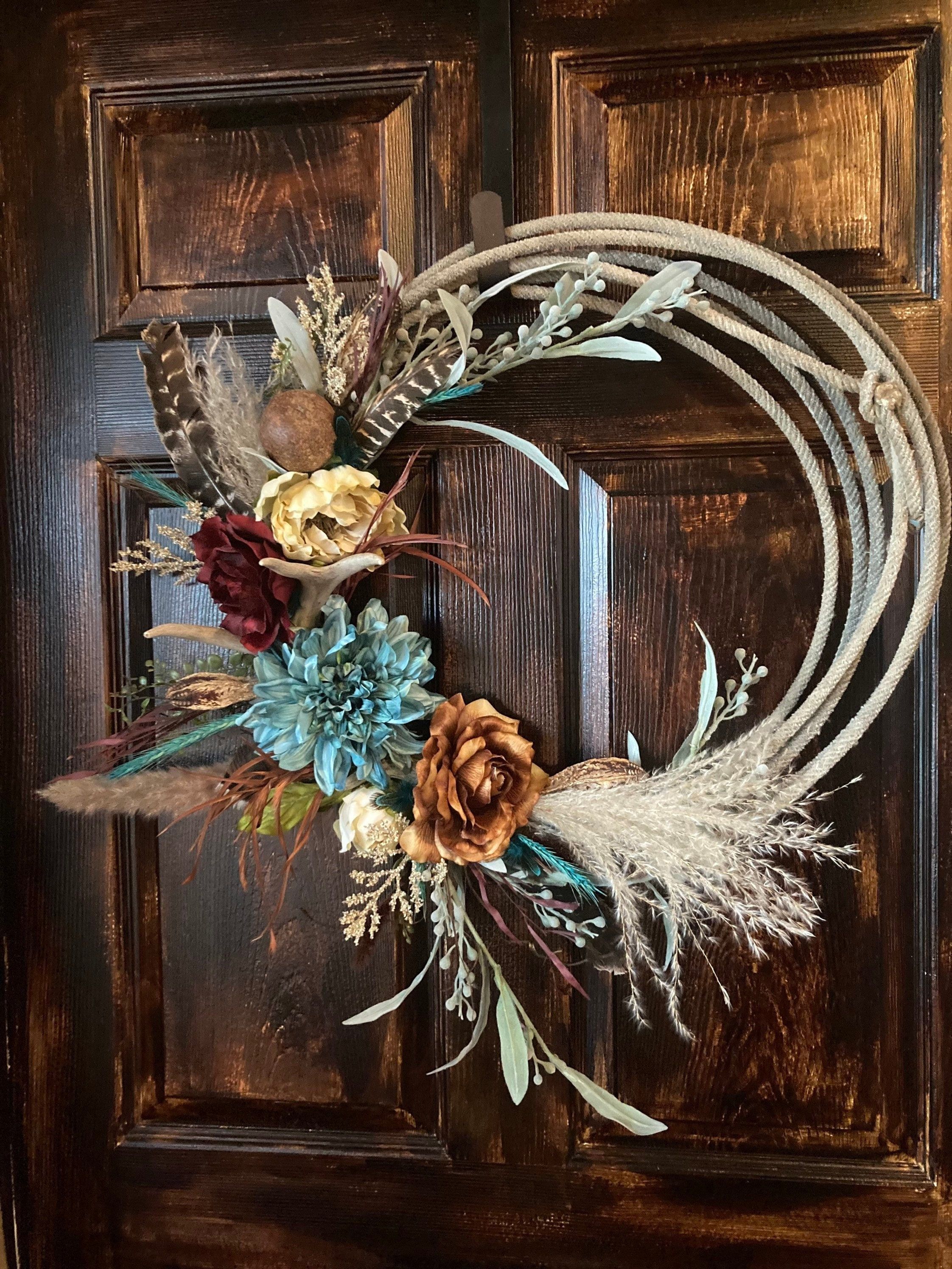 "Custom Rope wreath adorned with greenery, silk flowers, feathers, pods and antler. 20-22\" in diameter, with flowers added it measures approximately 24\" wide x 26\" tall These are used genuine ropes, they will have burn marks and aren't new which add character to your wreath! *NOTE: I can re-create a wreath, but no two wreaths will be exactly identical. Please provide me with the color of rope you would like (If I have that color on hand), type and color of flowers, feathers, greenery, pods, e Rope Wreath Diy, Antler Wreath, Feather Wreath, Wreath Crafts, Lariat Rope Crafts, Hunting Wreath, Boho Wreath, Feather Decor, Wreath Ideas