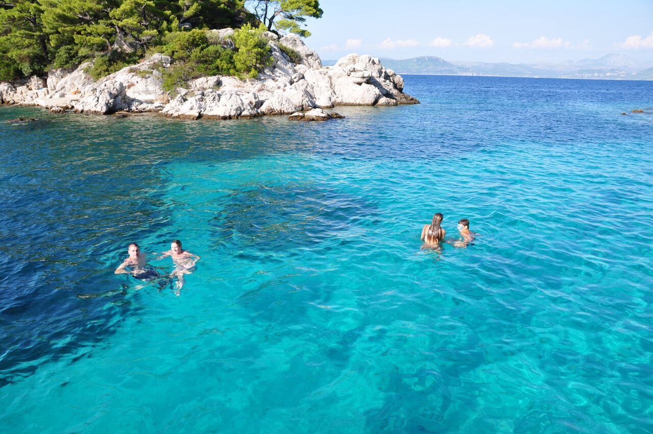 Three People Swimming In Clear Blue Water Near An Island three-people-swimming-in-clear-blue-water-near-an-island