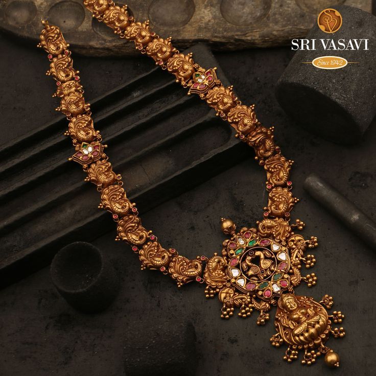 This 22kt nature-inspired necklace is the very epitome of traditional charm. the neckpiece features peacock-shaped patterns all along with the neckpiece, with an elaborate Peacock pendant. Hung with gold balls it studded kemp stones lend beauty to the jewel. Online Gold Jewellery, 22k Gold Jewelry, Gold Bride Jewelry, Gold Jewellery Design Necklaces, Indian Gold Necklace Designs, Antique Jewellery Designs, Antique Jewelry Indian, Kundan Jewellery Bridal, Indian Bridal Jewelry Sets