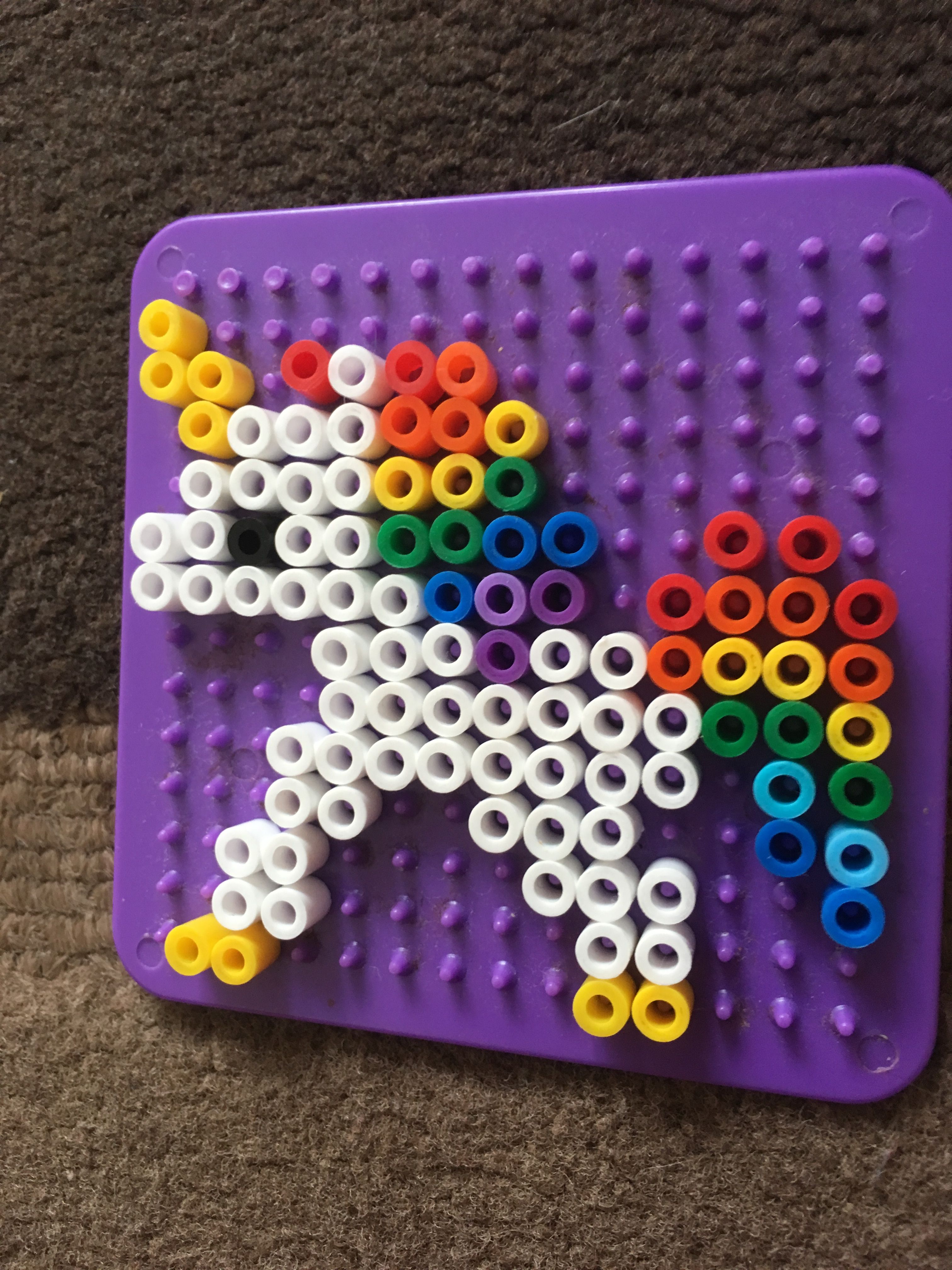A Purple Peg Board With White And Multicolored Beads On It Sitting On a-purple-peg-board-with-white-and-multicolored-beads-on-it-sitting-on