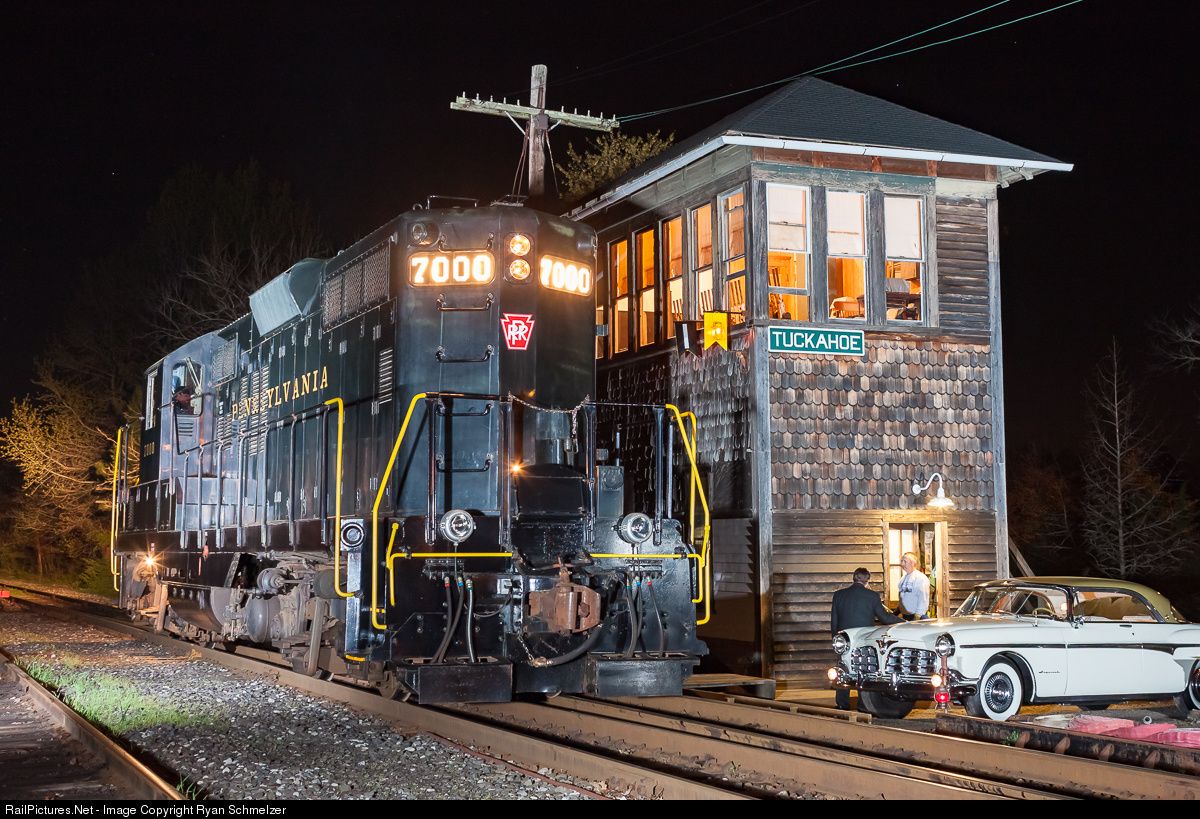 an old train is on the tracks at night with its lights on and people
