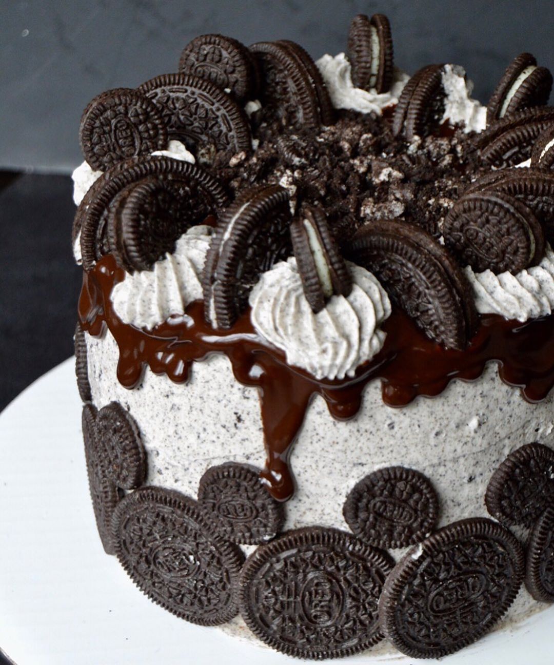 A Cake With Oreo Cookies And Cream Frosting Sitting On Top Of A White Plate