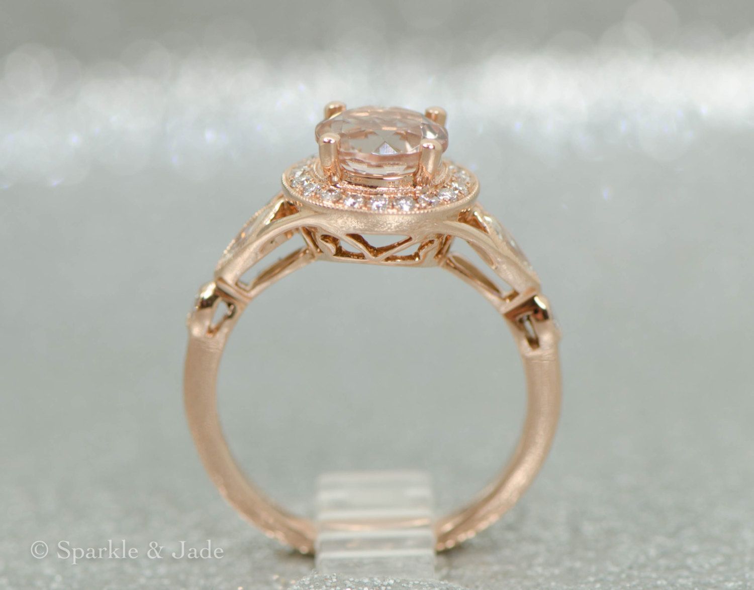Designed in the USA! Metal Material: 14k Rose Gold (solid) Filigree Undercarriage 7.10mm Top Ring Height 10mm Top Ring Width (Halo) Tappers To 2.35mm Width Band Stone Type: Diamond, Natural -- conflict-free! Grade SI-GH 2 - 4.20x2.40mm Marquise Cut Side Accents 2 - 1.70mm Round Cut Side Accents 21 - 1.00mm Round Halo Stones Stone Type: Morganite, Natural 7mm Round Grade AA, Eye Clean - Excellent Clarity 1.25CT Milgrain beadwork accents surrounding the halo and side stones. Stock Size: 6. Ready t Vintage Inspired Engagement Rings, Engagement Ring Sizes, Round Halo, Round Cut, Round Morganite, Top Rings, Marquise Cut, Conflict Free, Halo Diamond